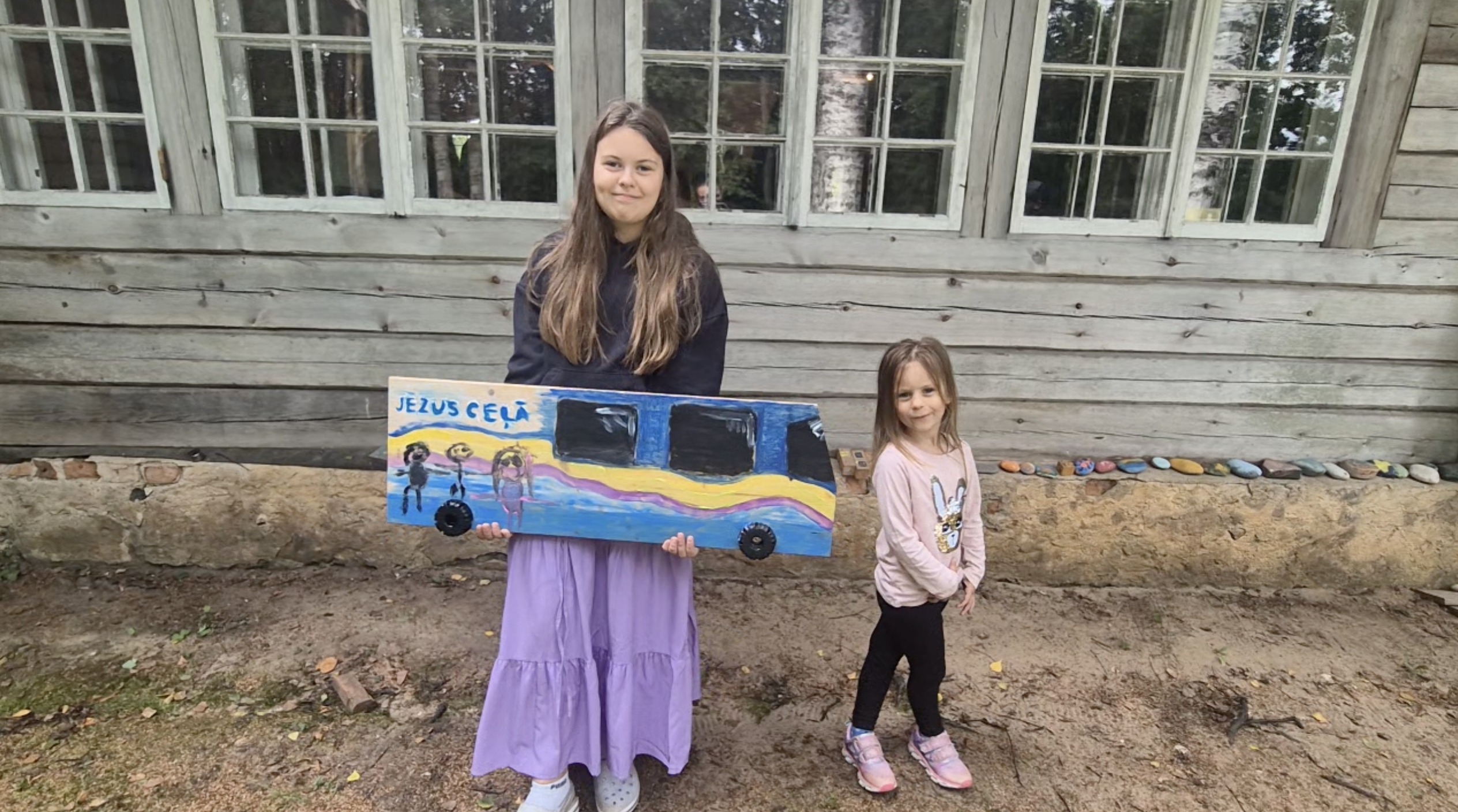 Meitenes ar pašdarinātu autobusa maketu